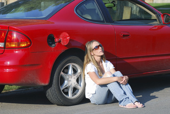 girl sitting beside car out of gas